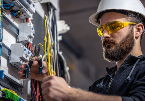 male-electrician-works-switchboard-with-electrical-connecting-cable
