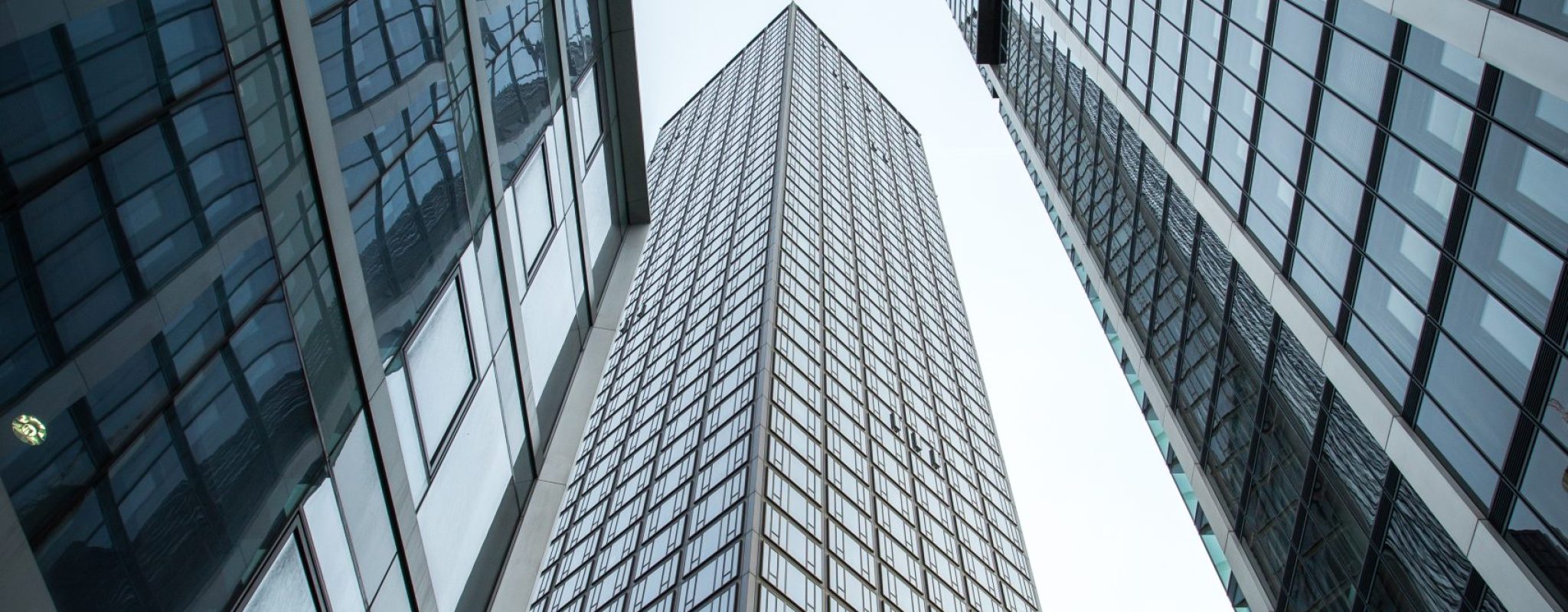 A vertical low angle shot of high rise skyscrapers in a glass facade in Frankfurt, Germany